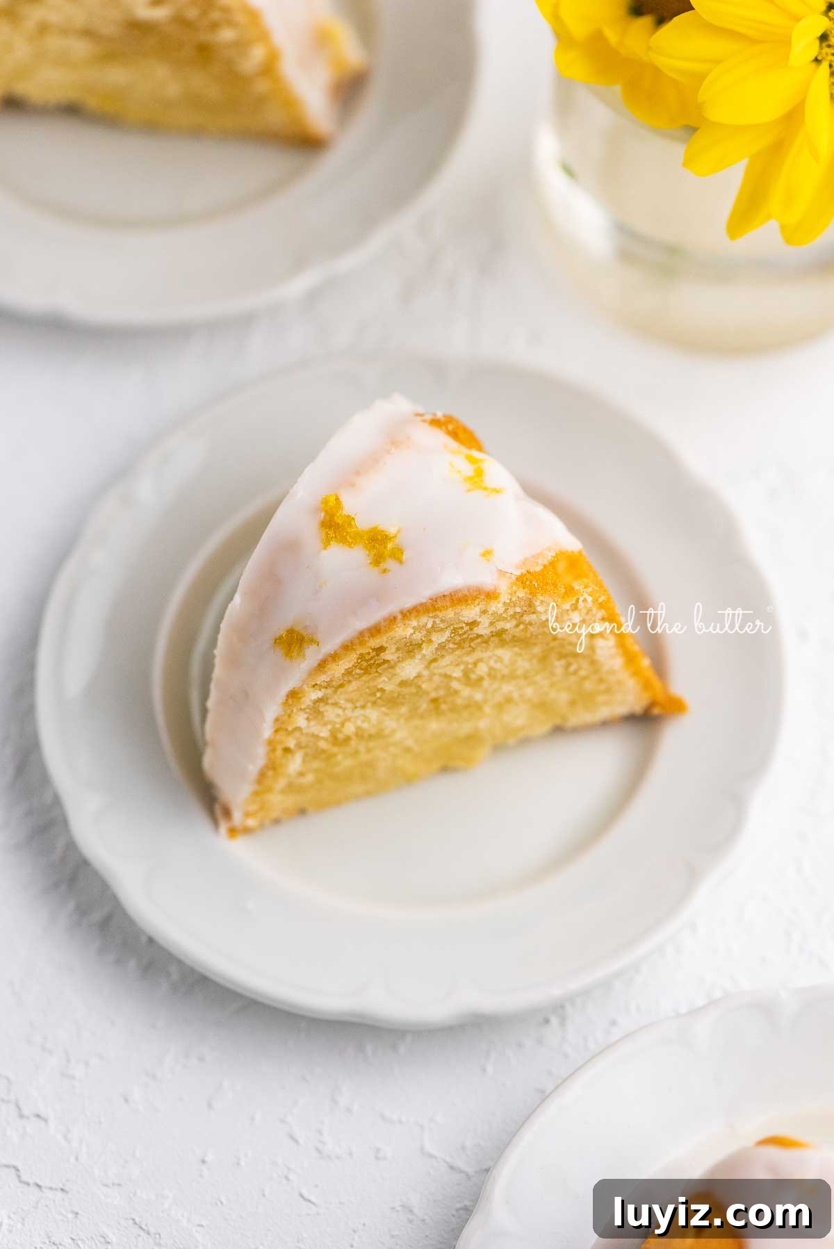 Moist Lemon Cream Cheese Pound Cake Recipe 4 Small lemon cream cheese pound cake slice on a small dessert plate on white background | © Beyond the Butter®