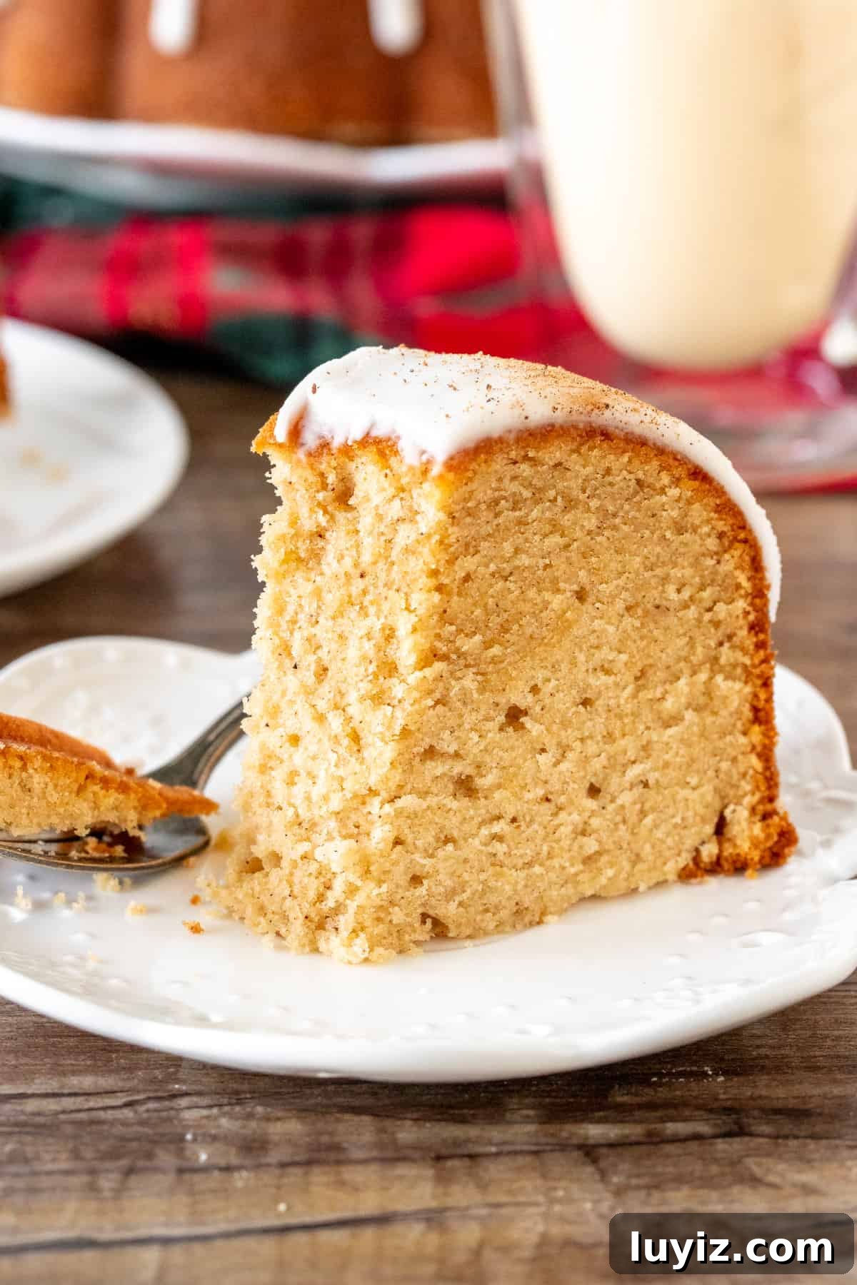 Moist Eggnog Bundt Cake Recipe Perfect for Christmas 5 Slice of eggnog pound cake with a bite taken out of it and a glass of eggnog