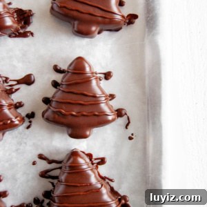 Chocolate-Covered Peanut Butter Christmas Tree Treats 7 Chocolate covered peanut butter trees on parchment paper lined baking sheet.