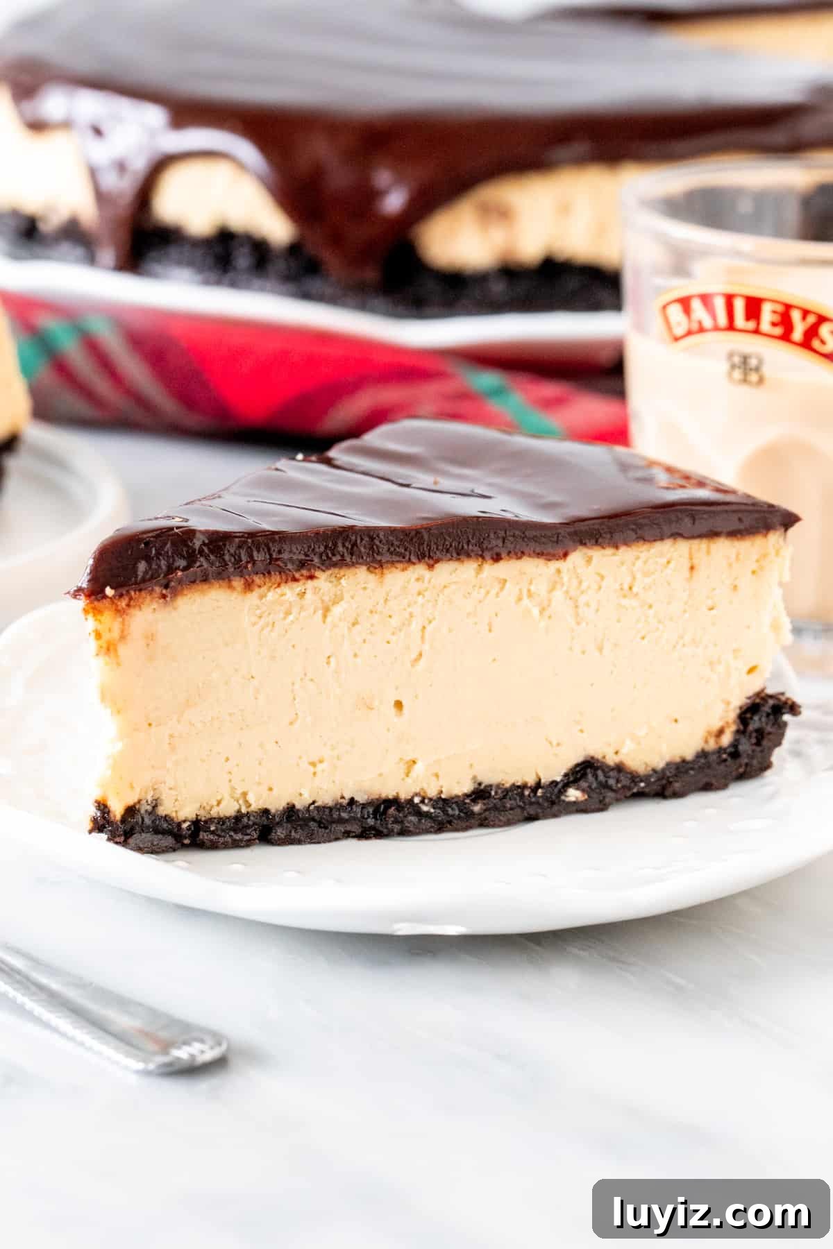 Baileys Cheesecake Recipe: Decadent Irish Cream Dessert 2 Slice of Baileys cheesecake with an Oreo crust and glass of Baileys