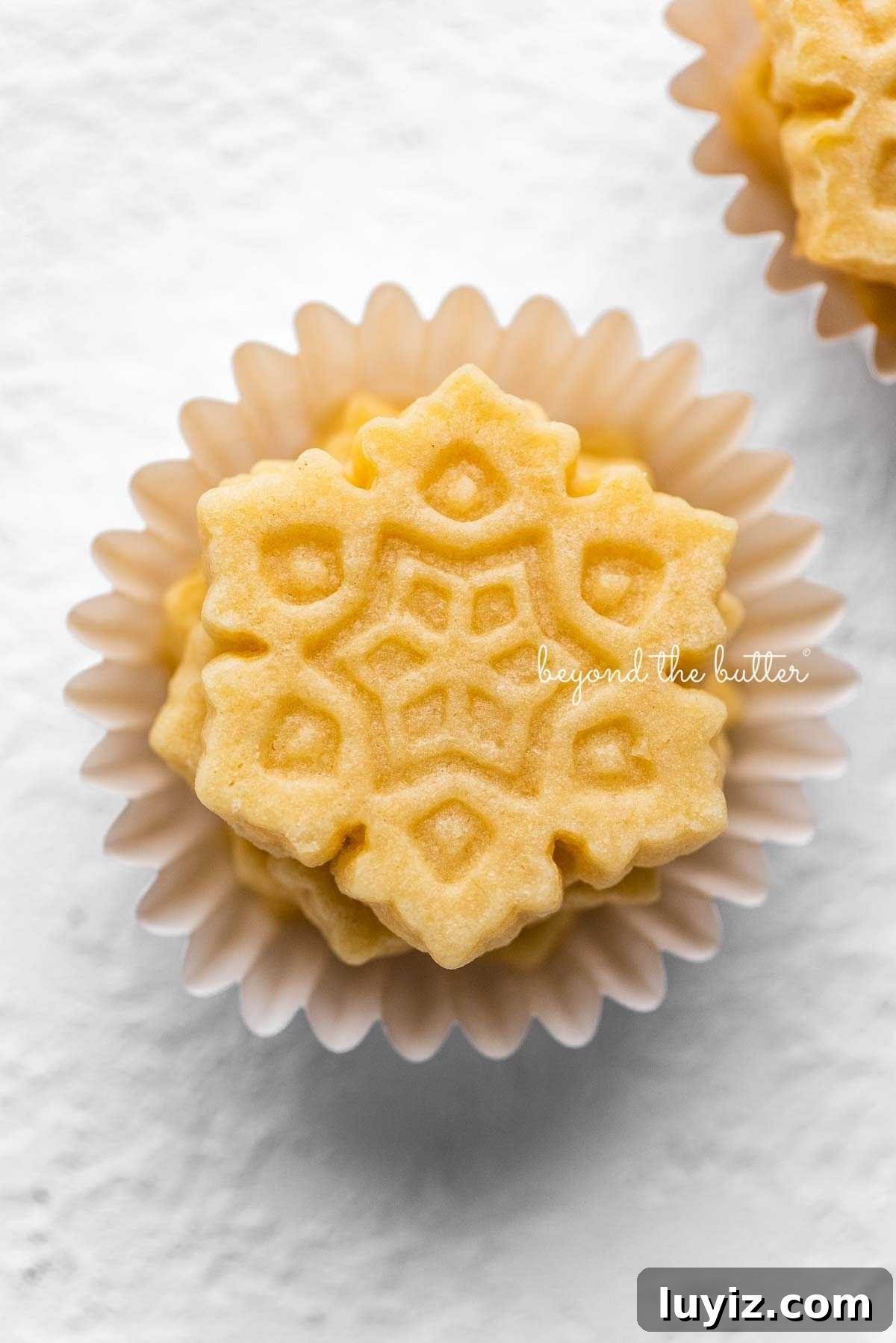 Classic Homemade Butter Cookies Recipe — Crisp, Melt-in-Your-Mouth Cookies 4 Stacks of butter cookies shaped as snowflakes in mini cupcake liners on a white background.