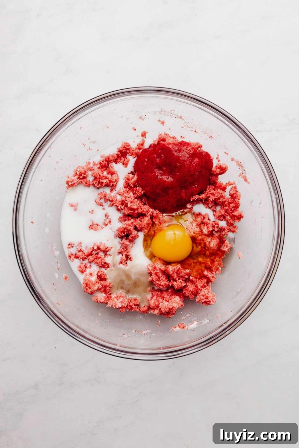 Mini Strawberry Sheet Cake Recipe: Quick Moist Fresh Strawberry Cake 12 Vanilla extract, milk, roasted strawberry puree, and an egg added to the top of the cake mixture in a glass mixing bowl.