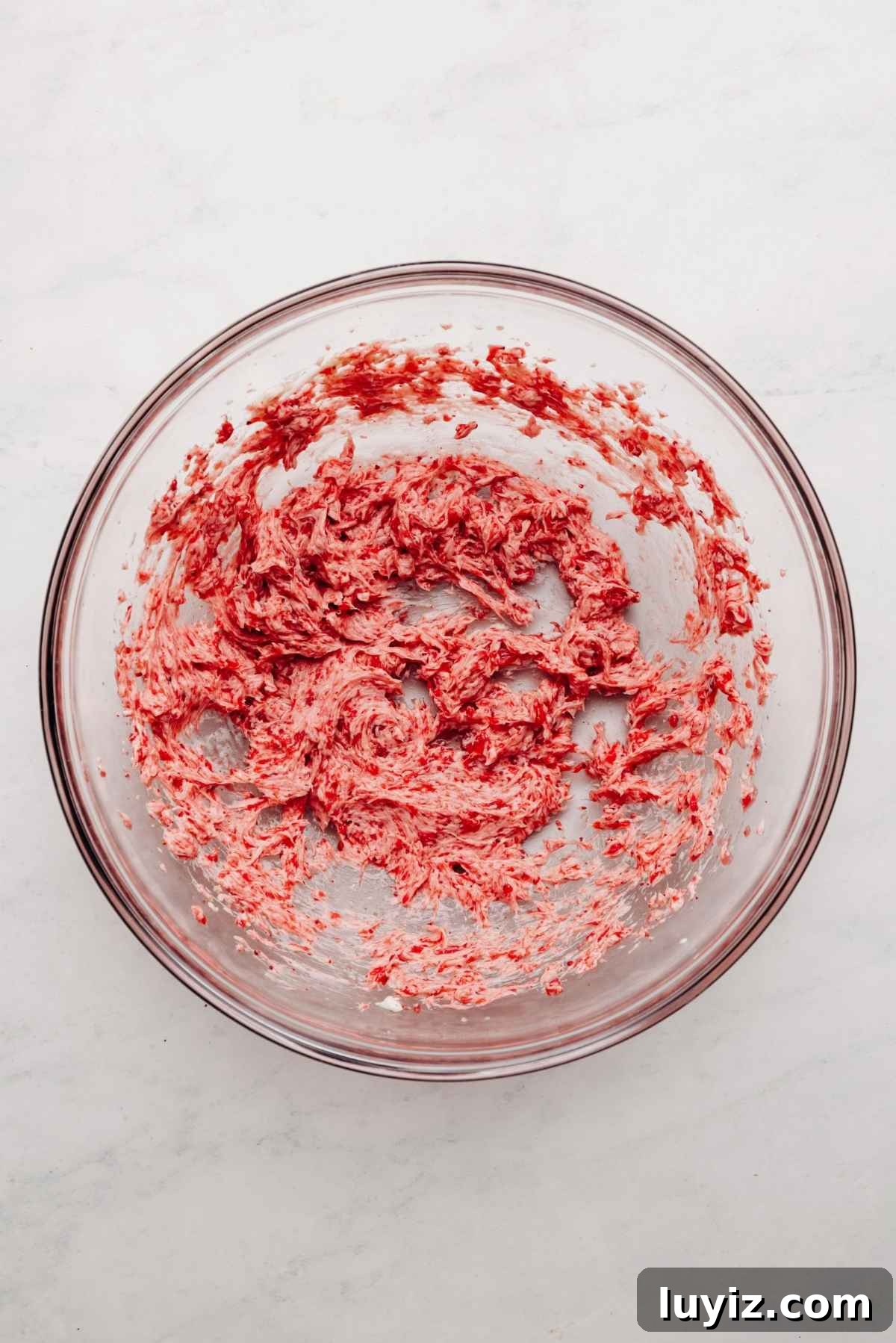 Mini Strawberry Sheet Cake Recipe: Quick Moist Fresh Strawberry Cake 17 Strawberry puree, freeze dried strawberry powder, butter, and salt blended together in a large glass mixing bowl on a white and grey textured background.