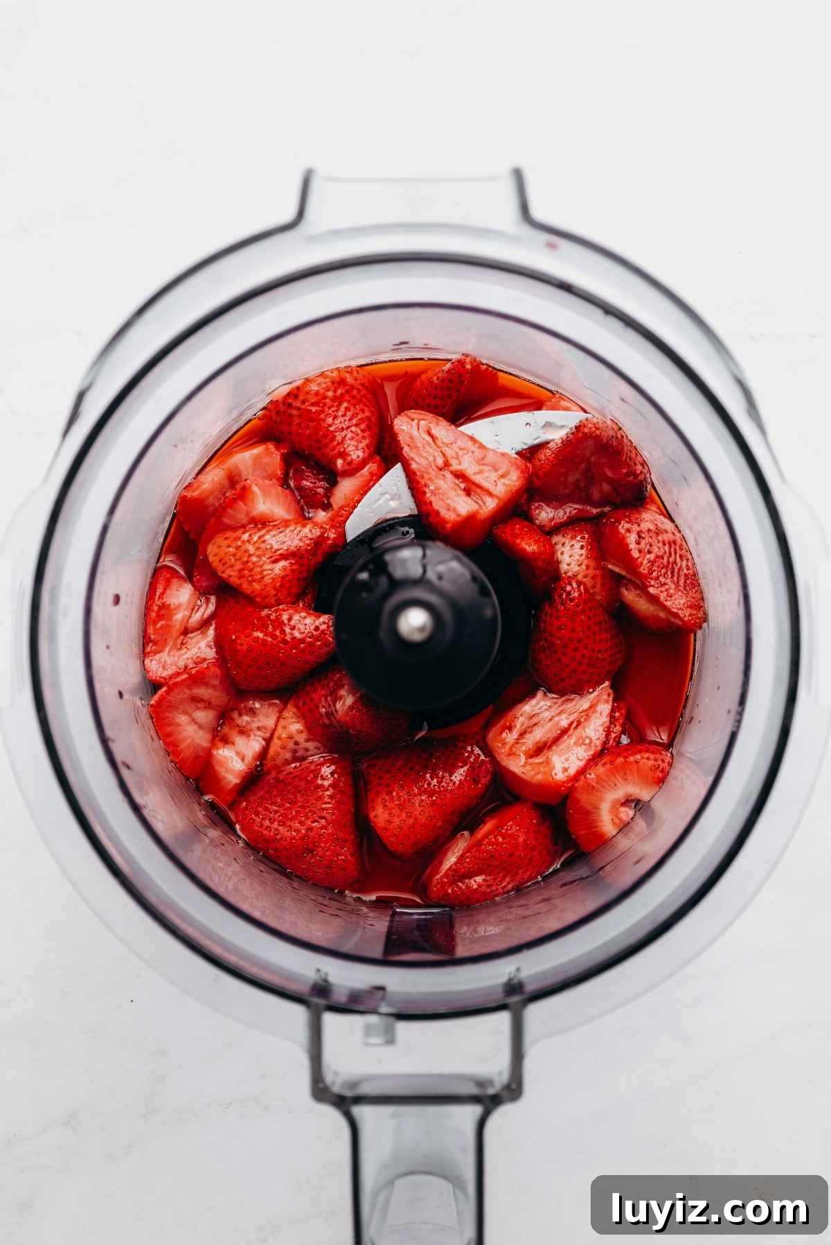Mini Strawberry Sheet Cake Recipe: Quick Moist Fresh Strawberry Cake 8 Roasted strawberries in a food processor on a white and grey textured background.