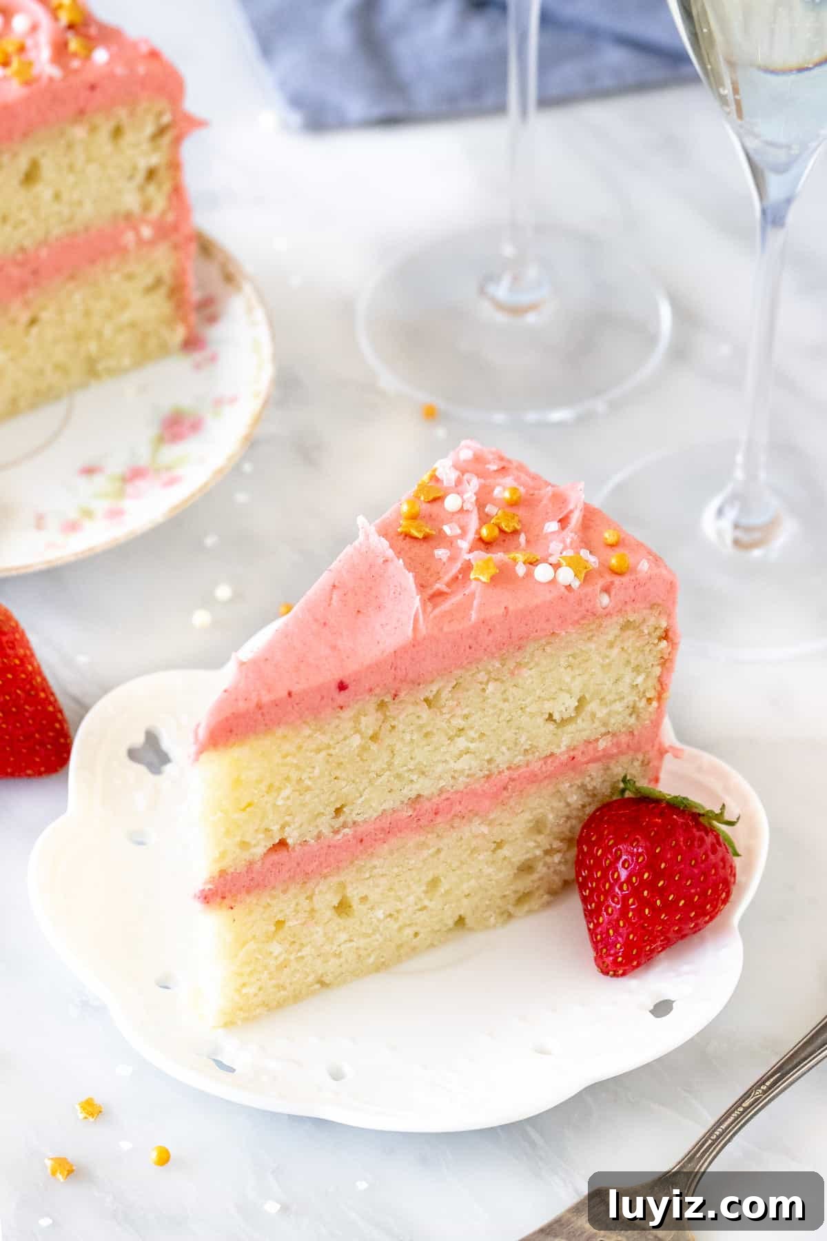 Strawberry Champagne Layer Cake Recipe for Celebrations 4 Slice of cake with pink frosting with 2 glasses of sparkling wine