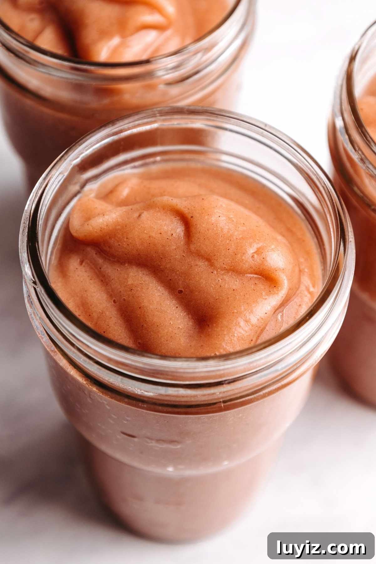 Homemade Applesauce Without Added Sugar: Simple Recipe 10 Homemade cinnamon applesauce in glass ball jars on a white background.
