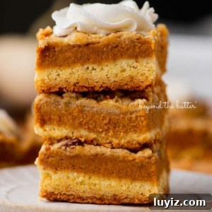 Pumpkin Pie Bars with Creamy Cinnamon Filling 12 Stack of three pumpkin pie cake bars on a parchment paper lined bottom.