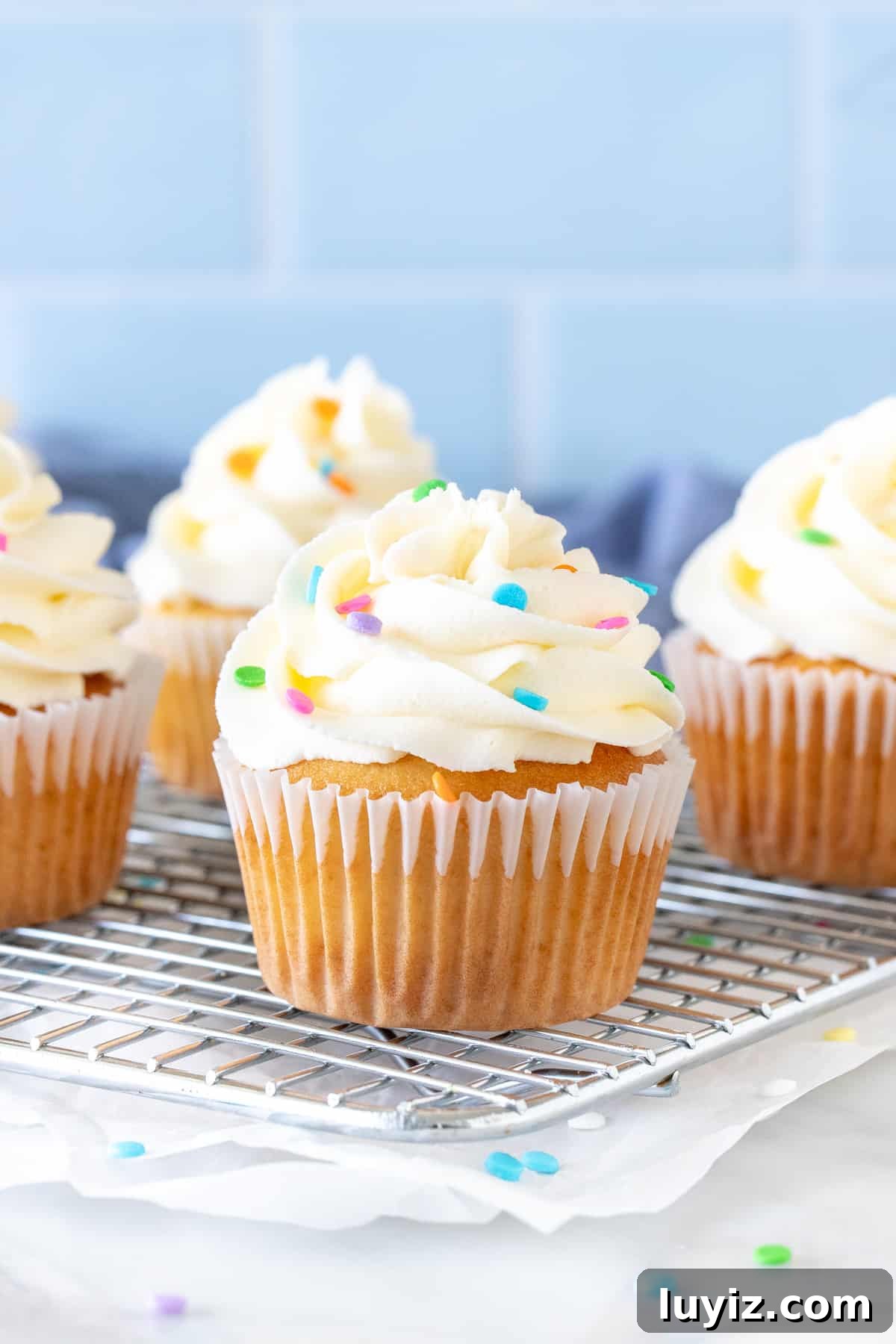 Perfect White Frosting Recipe: How to Make Smooth White Icing 6 Cupcakes on a wire rack with bright white frosting