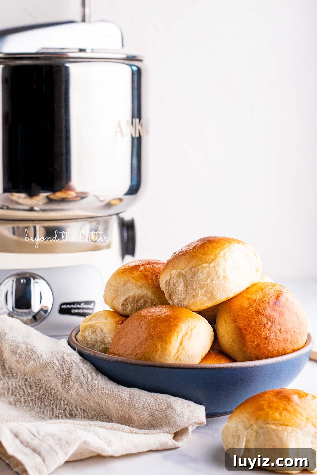 Soft Honey Butter Dinner Rolls Recipe for Fluffy, Golden Buns 4 Honey butter dinner rolls in a blue ceramic bowl made with the Ankarsrum Original Mixer | © Beyond the Butter®