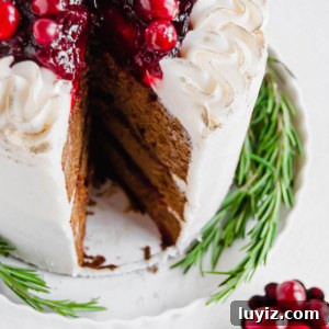 Classic Gingerbread Cake Recipe with Warm Spices 7 3 layer gingerbread cake with maple buttercream frosting, topped with a cranberry compote with a slice removed.