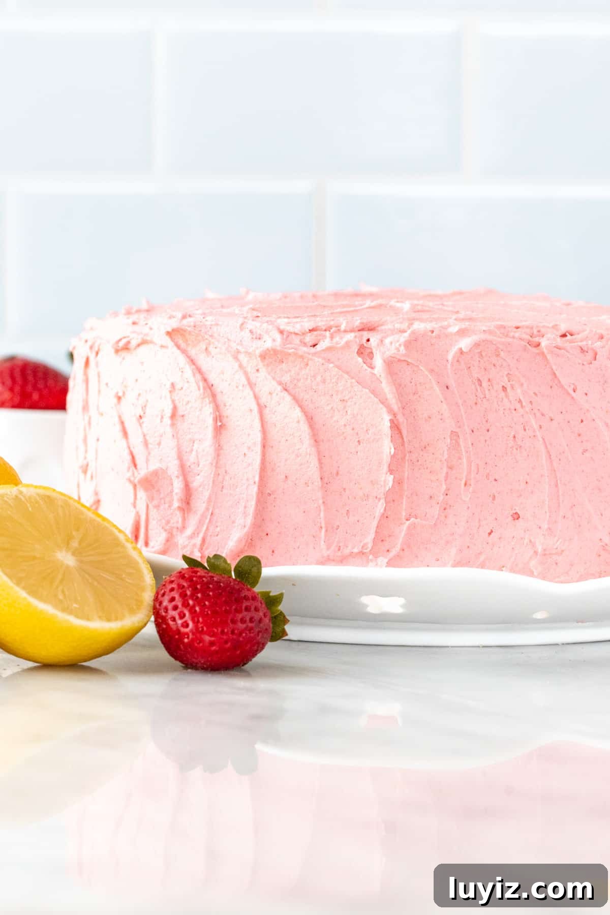 Strawberry lemon cake on a round cake plate.