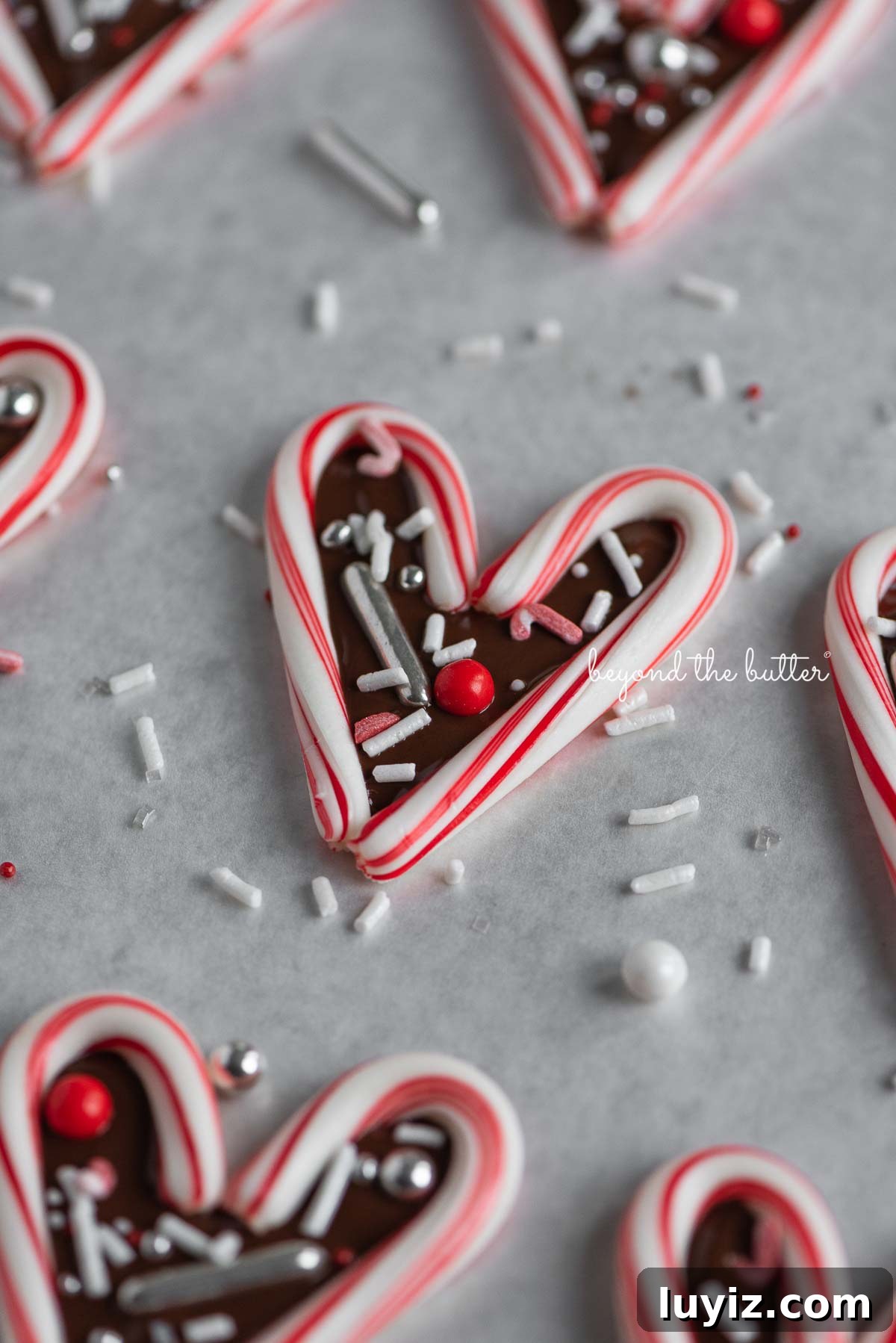 Candy Cane Heart Cookies: Festive Holiday Treats & Gift Ideas 3 Candy cane hearts on parchment paper | © Beyond the Butter®