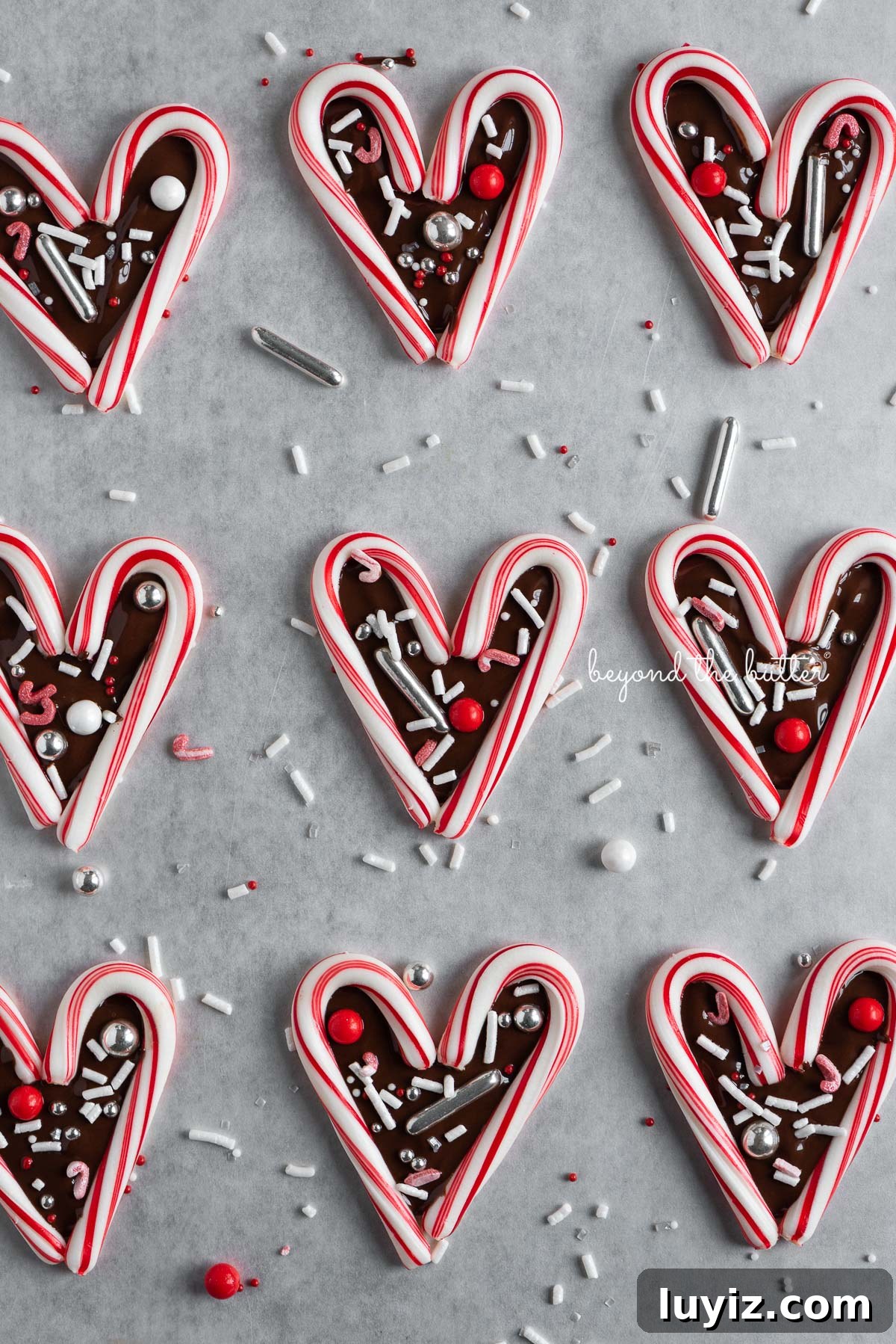 Candy Cane Heart Cookies: Festive Holiday Treats & Gift Ideas 6 Fun candy cane hearts on parchment paper | © Beyond the Butter®