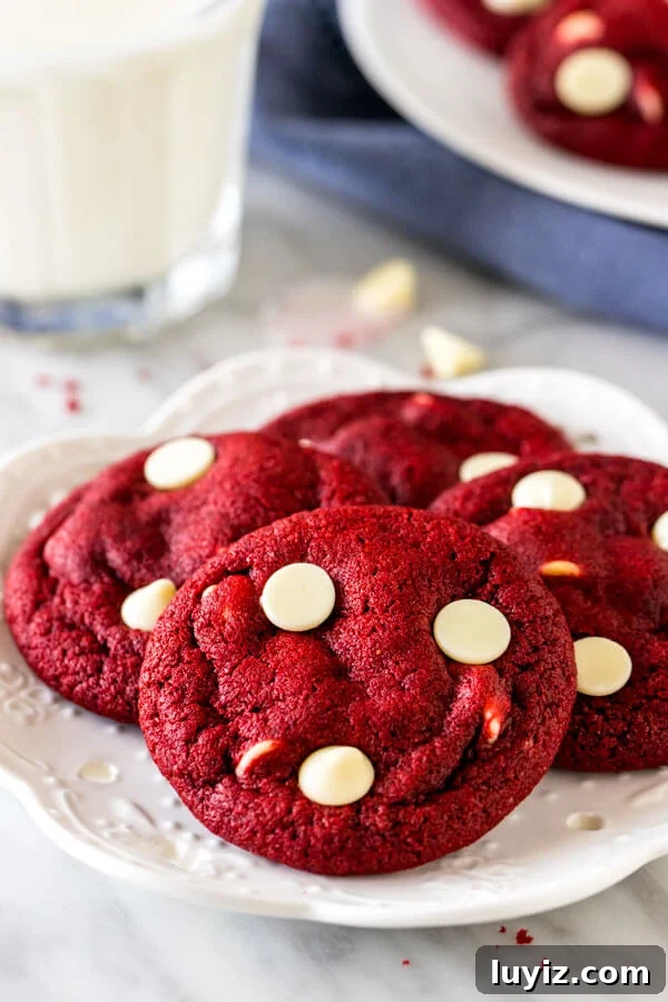 Red Velvet Chocolate Chip Cookie Recipe — Soft, Decadent Treats 2 A plate of red velvet white chocolate chip cookies with a glass of milk