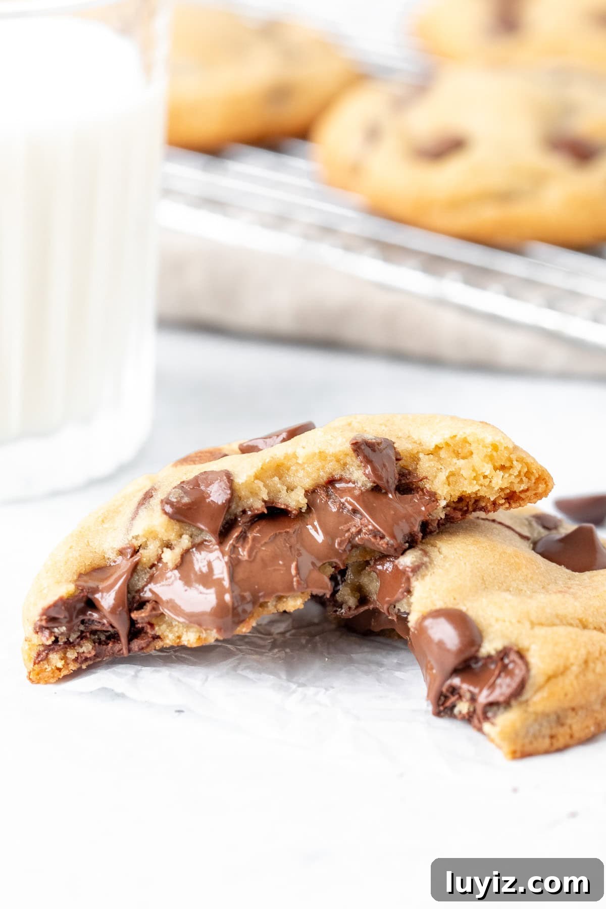 Decadent Nutella-Filled Chocolate Chip Cookies 7 Nutella stuffed cookie broken in half with glass of milk