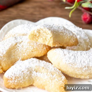 Plate of almond crescent cookies, with one cookie broken in half