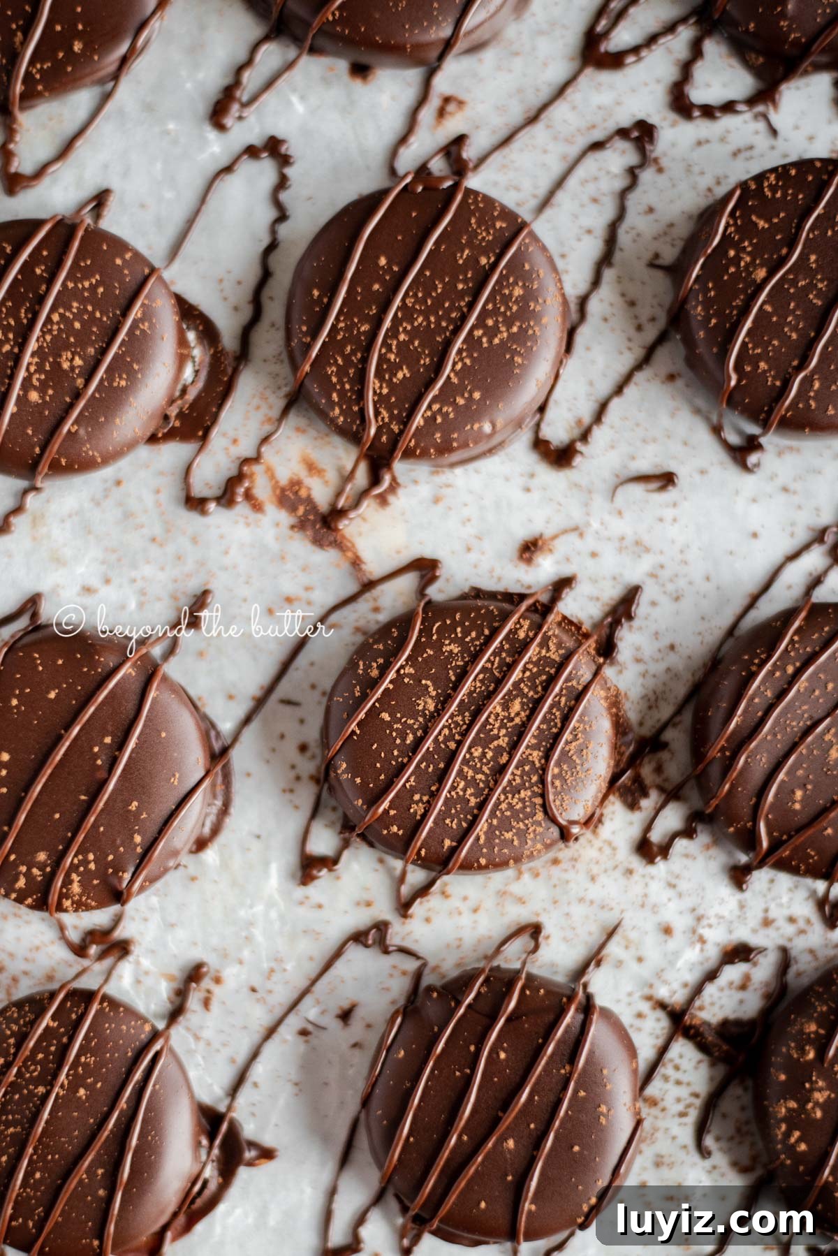 How to Make Classic Homemade Peppermint Patties at Home 8 Round chocolate dipped peppermint patties drizzled with chocolate and dusted with cocoa powder on wax paper lined baking sheet.
