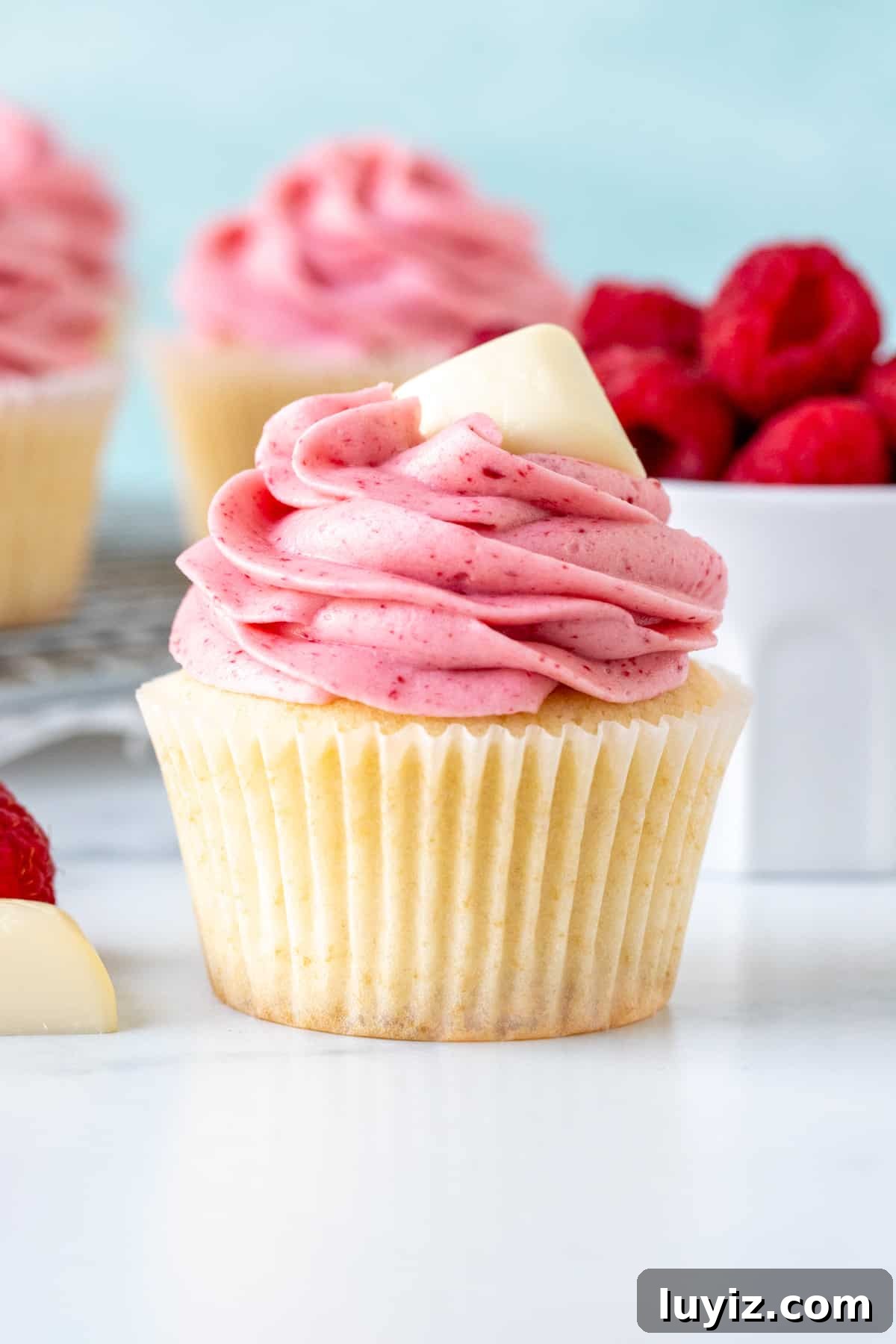 White Chocolate Raspberry Cupcakes Recipe for Decadent Treats 2 White chocolate raspberry cupcake with small bowl of berries