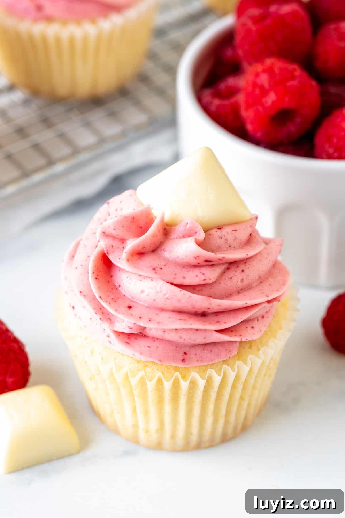White Chocolate Raspberry Cupcakes Recipe for Decadent Treats 3 White chocolate cupcake with white chocolate raspberry frosting and topped with square of white chocolate