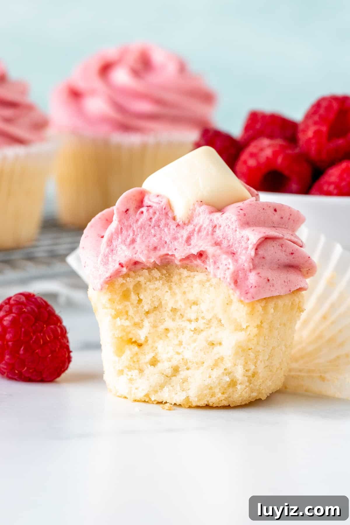 White Chocolate Raspberry Cupcakes Recipe for Decadent Treats 4 White chocolate cupcake with raspberry frosting with a bite taken out