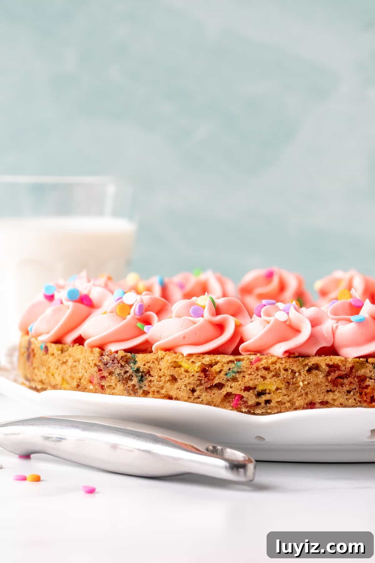 Funfetti Cookie Cake Recipe with Sprinkle-Filled Frosting 2 9-inch round funfetti cookie cake with pink frosting around the edges.
