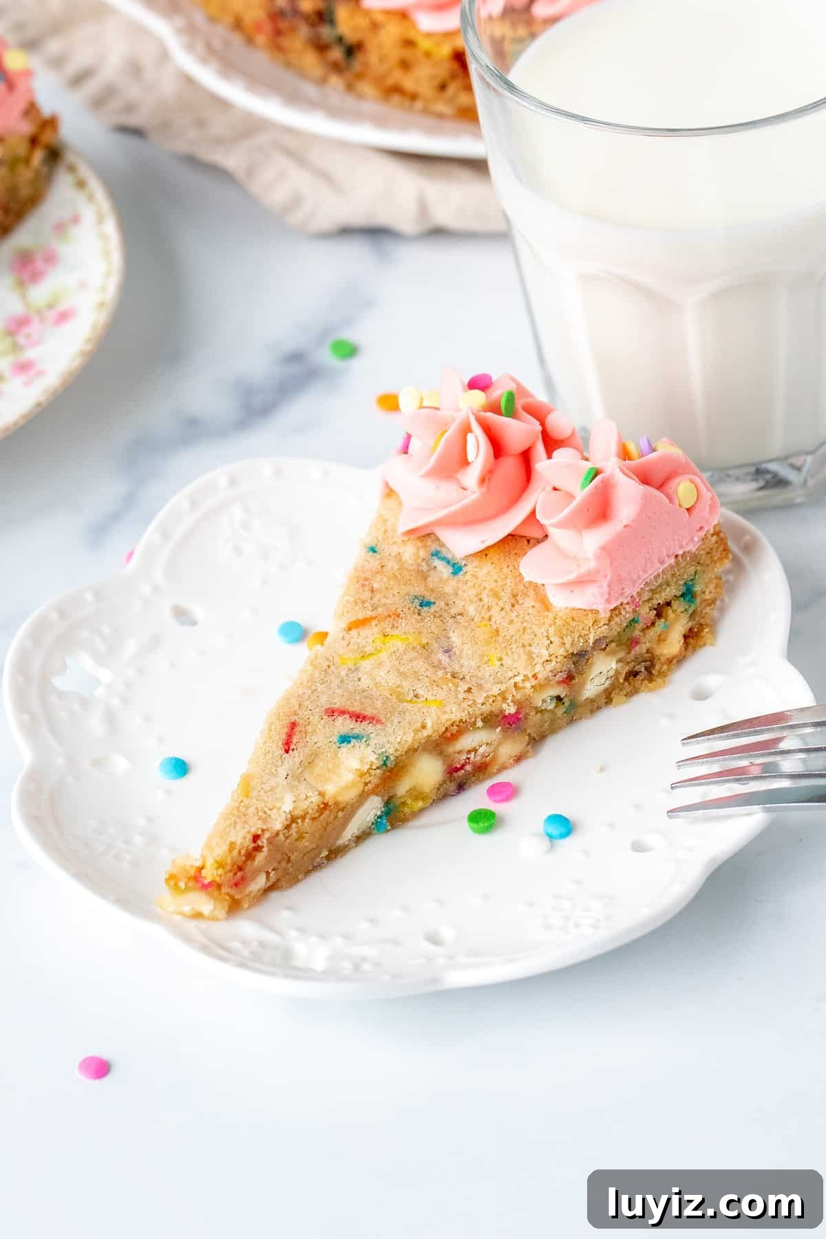 Funfetti Cookie Cake Recipe with Sprinkle-Filled Frosting 3 Slice of sprinkle sugar cookie cake with pink frosting