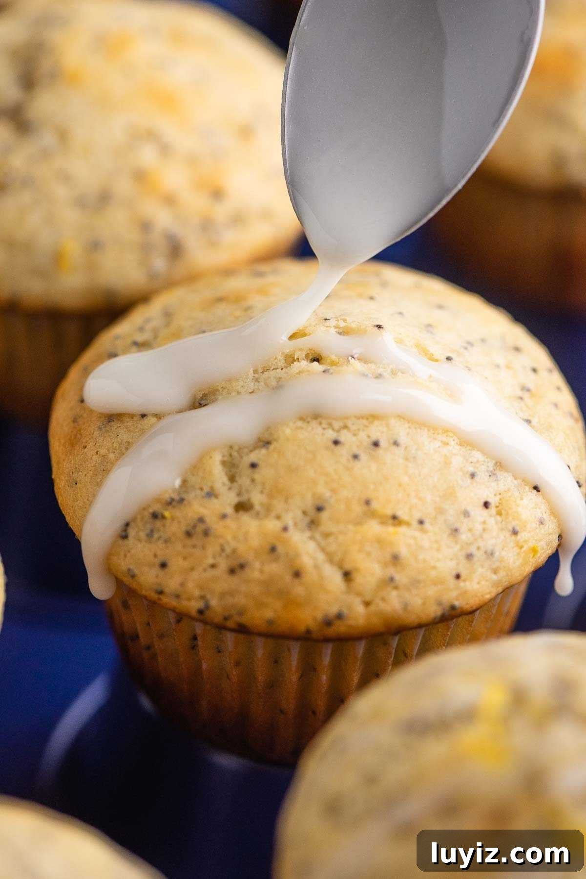 Lemon Poppy Seed Muffins with Zesty Glaze Recipe 11 Drizzling lemon glaze over lemon poppy seed muffins using a spoon.