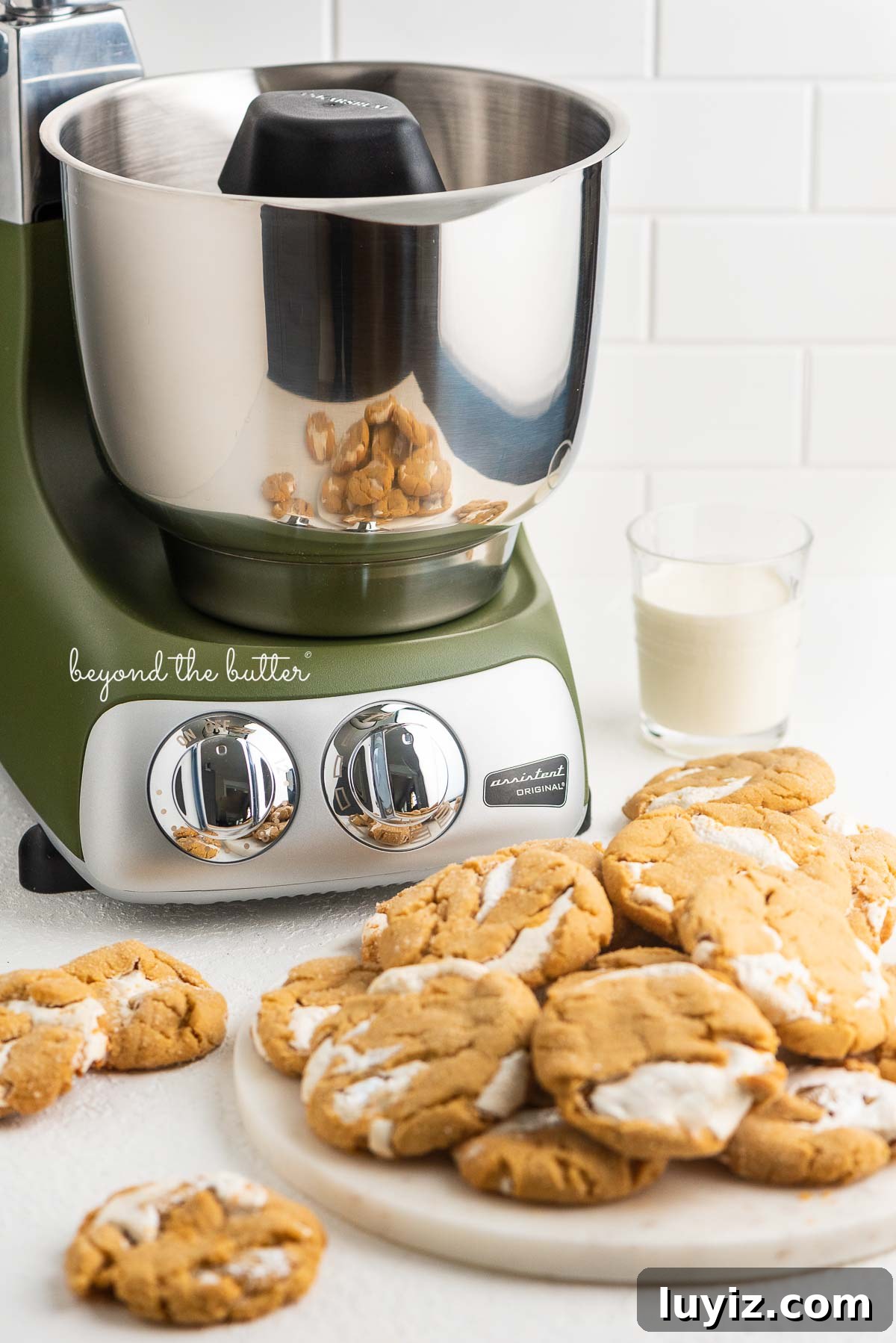 Fluffernutter Sandwich Cookies with Peanut Butter & Marshmallow Filling 4 Olive green Ankarsrum stand mixer with fluffernutter cookies and glass of milk on white background.
