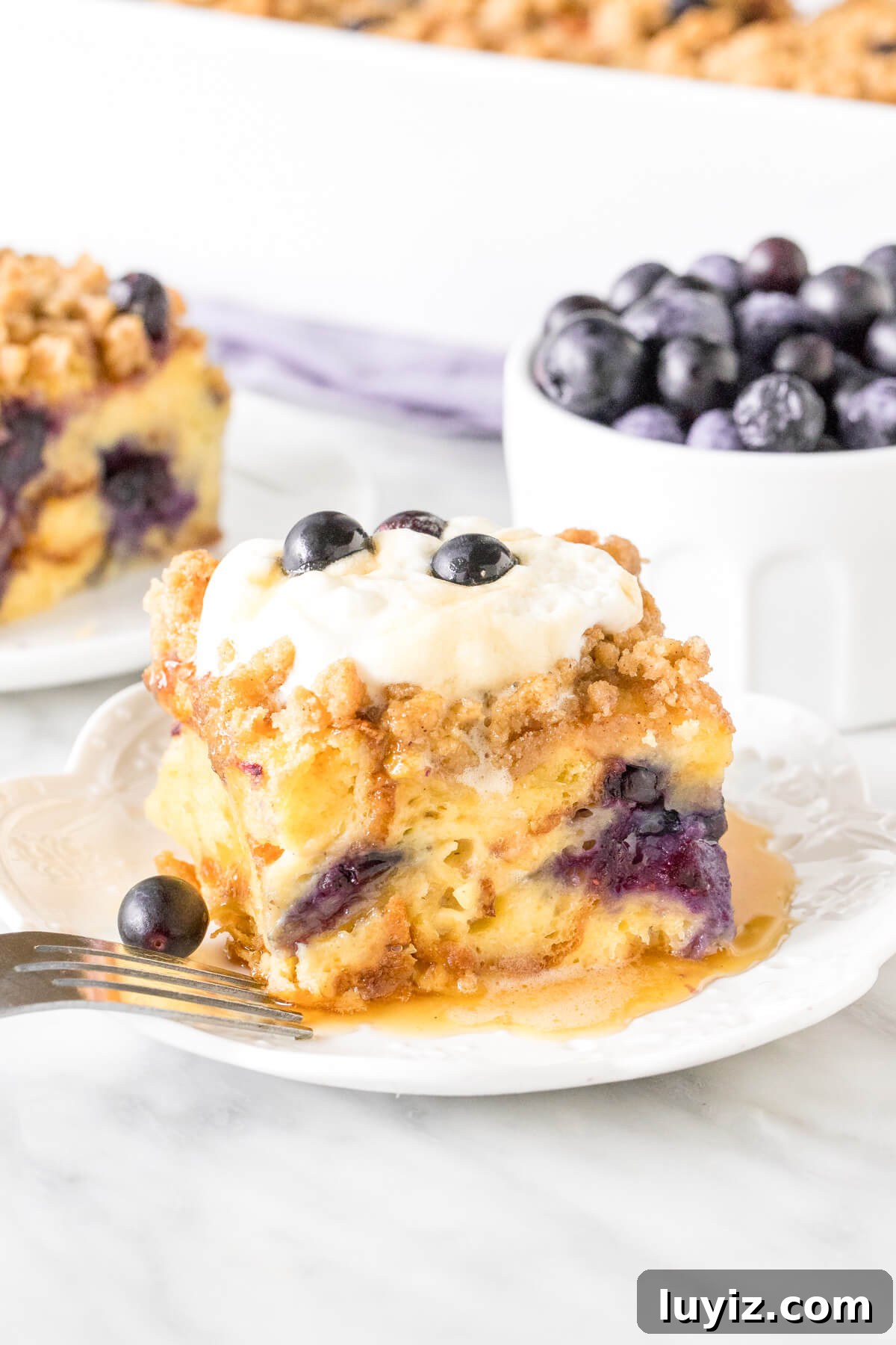 Mother’s Day Brunch & Dessert Ideas: Sweet Breakfast Recipes 4 Slice of blueberry french toast casserole with whipped cream on top.