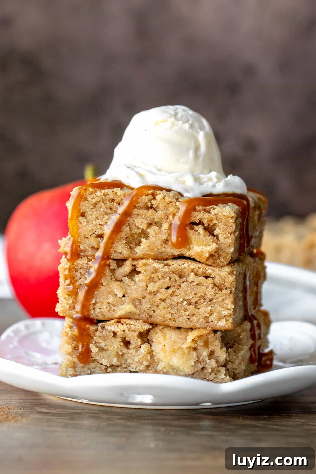 Cinnamon Apple Blondies — Soft, Chewy, Spiced Bite-Sized Treats 2 Stack of 3 caramel apple blondies on top of each other, topped with scoop of ice cream and drizzle of caramel
