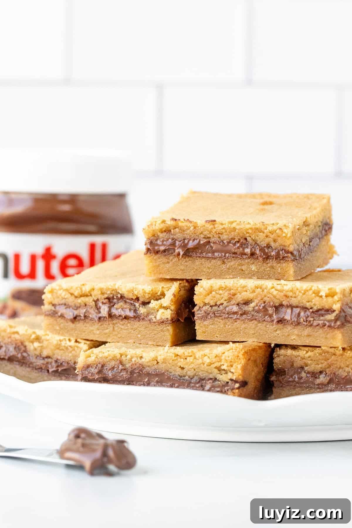 Nutella-Stuffed Blondies: Gooey Chocolate-Hazelnut Bars 3 Plate of Nutella blondies with jar of Nutella