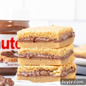 Nutella-Stuffed Blondies: Gooey Chocolate-Hazelnut Bars 10 Three Nutella stuffed blondies, one on top of each other with a jar of Nutella