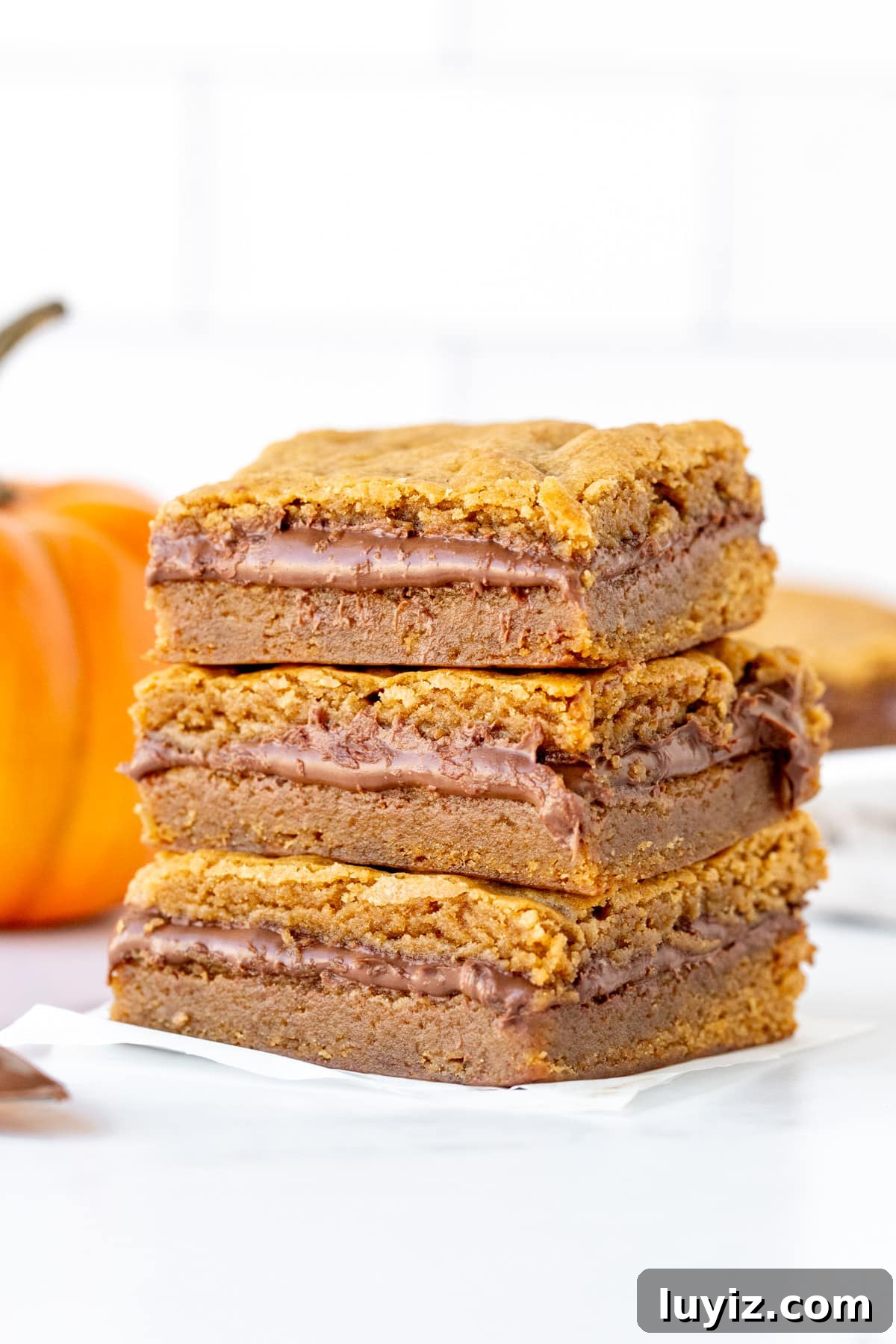 Three Nutella stuffed pumpkin blondies, stacked one on top of each other