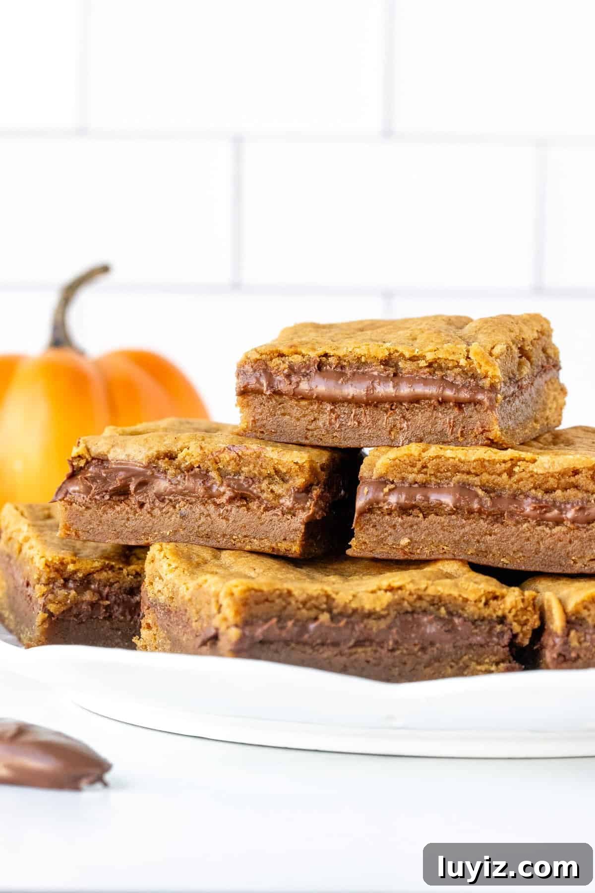 Nutella‑Stuffed Pumpkin Blondies with Gooey Chocolate Center 3 Plate of pumpkin Nutella cookie bars, stacked.