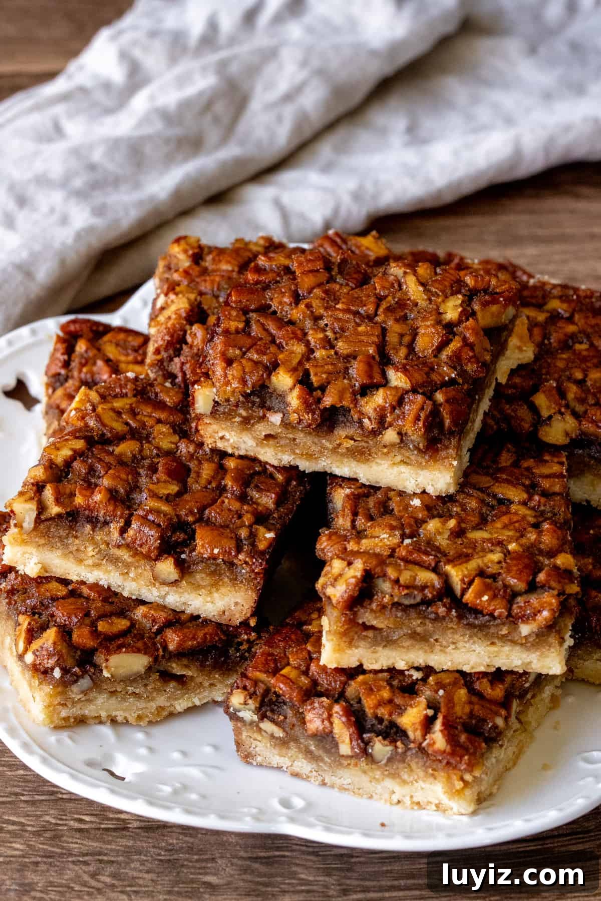 Irresistible Maple Pecan Bars Recipe with Gooey Caramel Filling 3 Plate of maple pecan shortbread bars, with bars stacked on top of each other