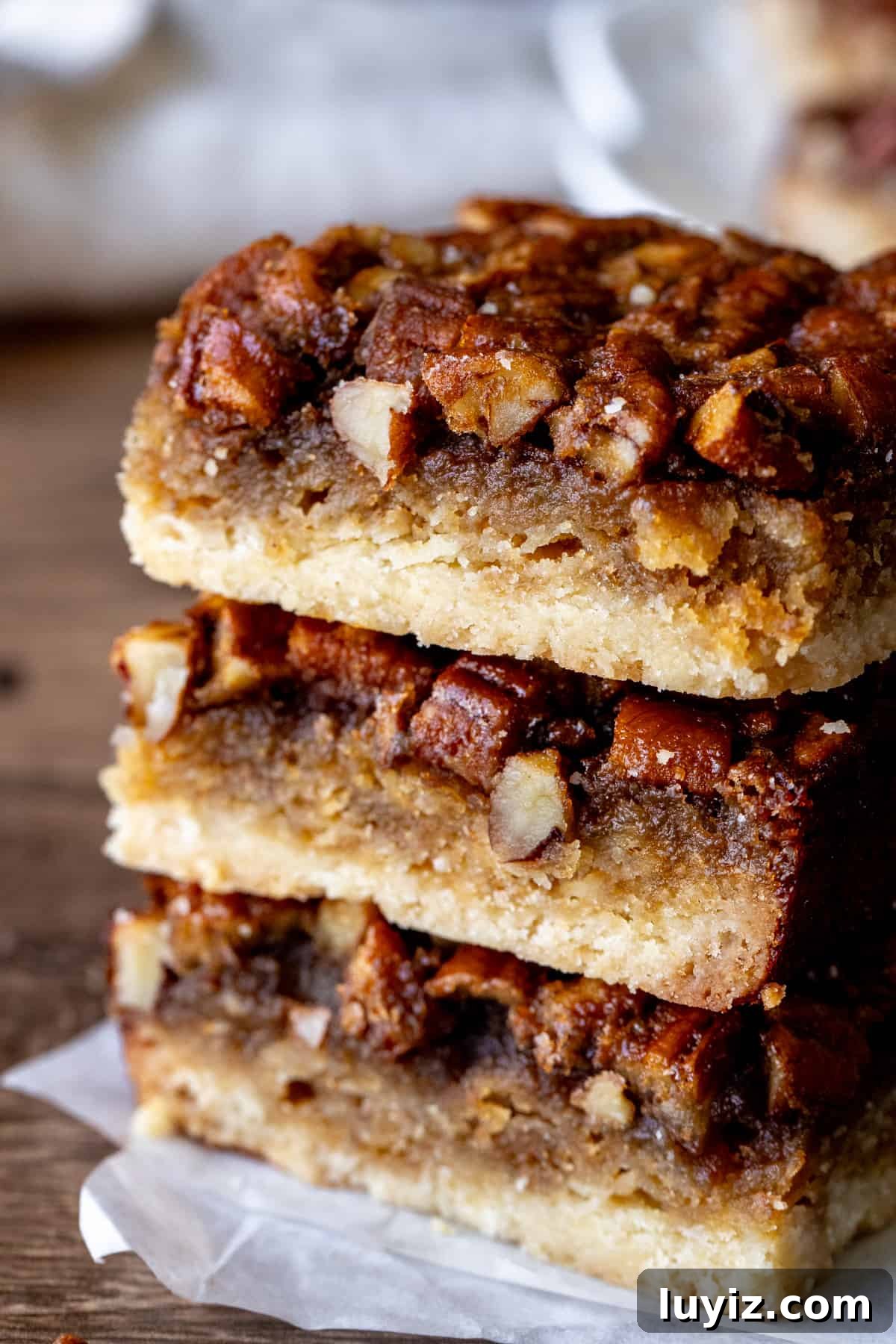 Irresistible Maple Pecan Bars Recipe with Gooey Caramel Filling 6 Three maple pecan pie bars, stacked one on top of each other.