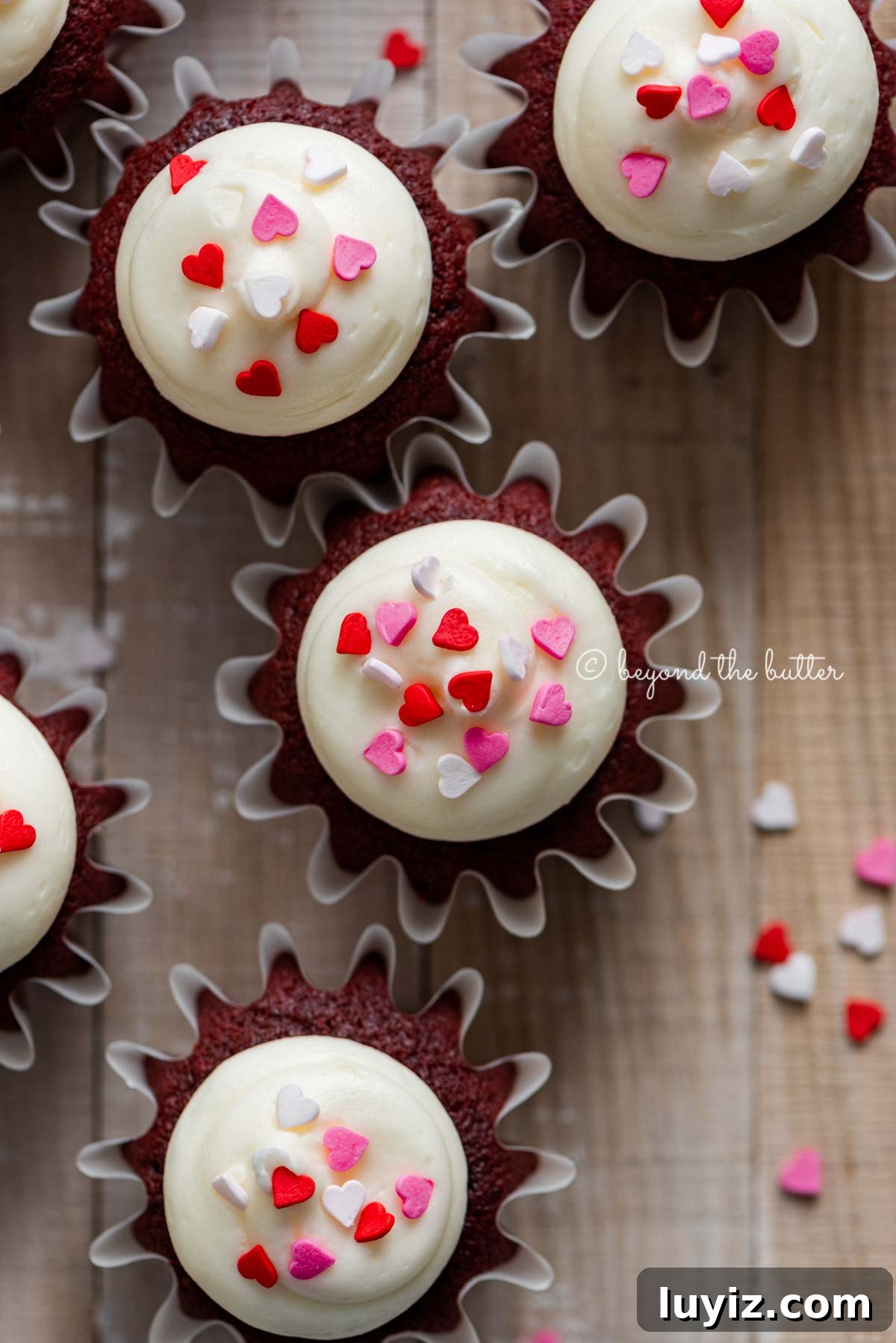 Perfect Red Velvet Cupcakes Recipe for Moist, Fluffy Results 17 Homemade red velvet cupcakes with cream cheese frosting topped with heart sprinkles on a light wood background | All images © Beyond the Butter®