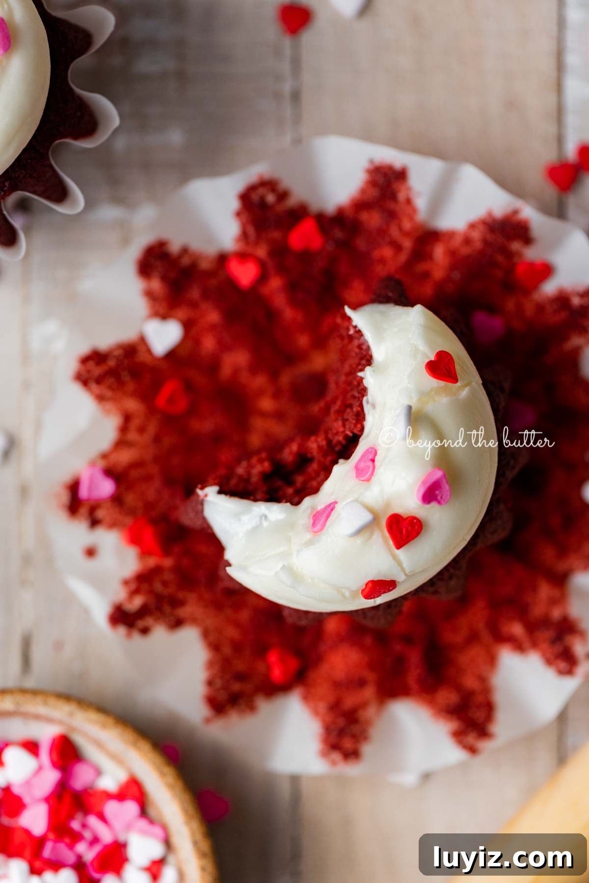 Perfect Red Velvet Cupcakes Recipe for Moist, Fluffy Results 4 Homemade red velvet cupcakes with one opened and half eaten with a small bowl of Valentine's Day sprinkles on light wood background | All images © Beyond the Butter®