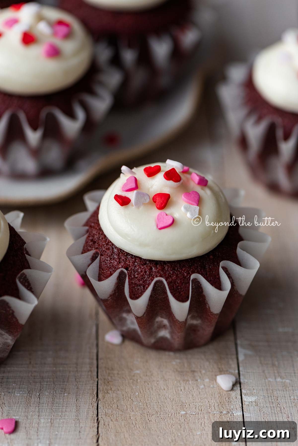 Perfect Red Velvet Cupcakes Recipe for Moist, Fluffy Results 9 Homemade red velvet cupcakes with cream cheese frosting topped with heart sprinkles on a light wood background | All images © Beyond the Butter®