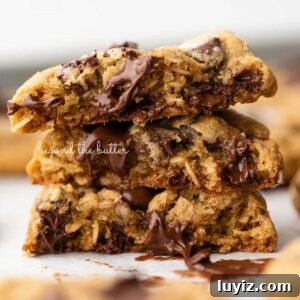 Salted Caramel Oatmeal Chocolate Chip Cookies 12 Stack of three oatmeal chocolate chip salted caramel cookies on a parchment paper lined baking sheet.