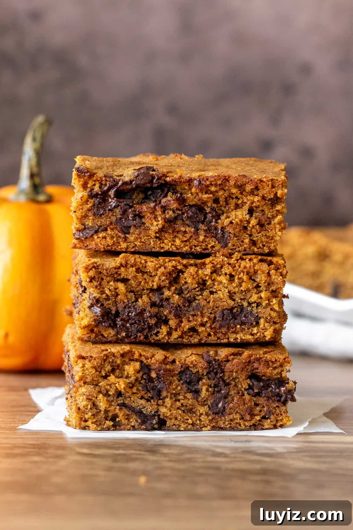 Pumpkin Chocolate Chip Blondies: Soft Fall Dessert Bars 7 Three pumpkin cookie bars, one on top of the other.