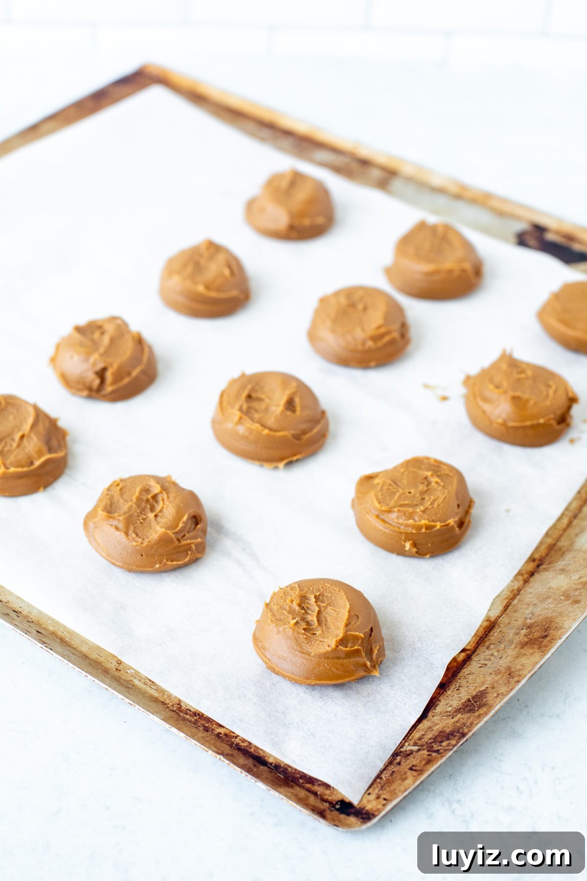 Biscoff Cookies Stuffed with Cookie Butter: Crispy, Gooey Treat 4 Spoonfulls of cookie butter on a lined cookie sheet