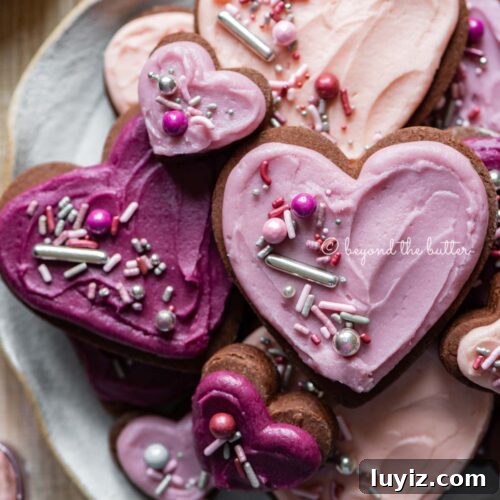 Plate full of heart-shaped chocolate cut out sugar cookies decorated with buttercream frosting and sprinkles.