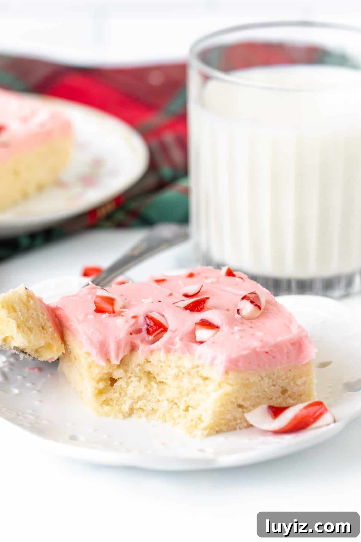 Peppermint Sugar Cookie Bars Recipe — Festive Holiday Dessert 8 Candy cane sugar cookie bar with bite taken out, with glass of milk