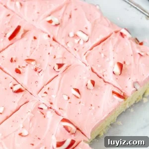 Peppermint Sugar Cookie Bars Recipe — Festive Holiday Dessert 9 Pan of frosted peppermint sugar cookie bars with crushed candy canes on top