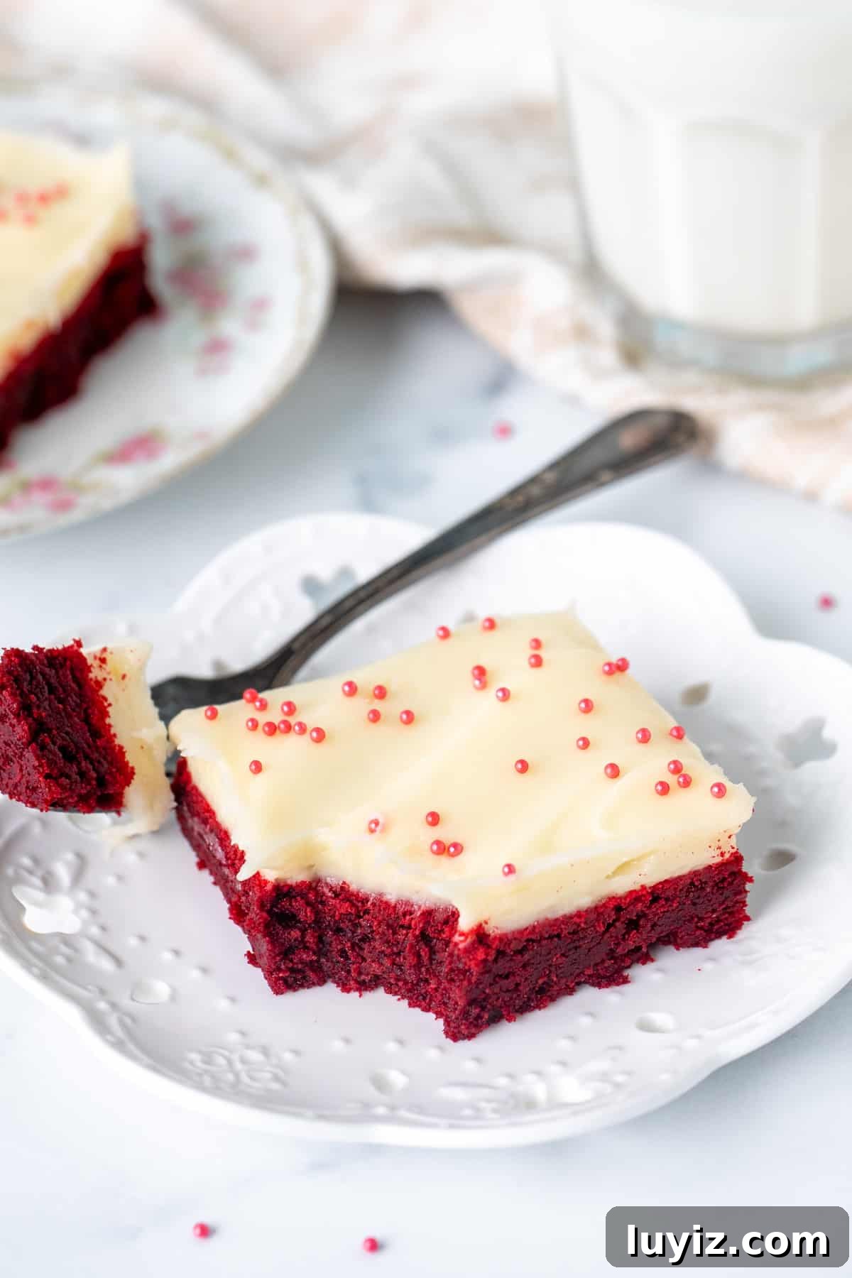 Chewy Red Velvet Cookie Bars Recipe for Parties and Gifts 2 Red velvet cookie bar with cream cheese frosting on a plate, with bite taken out