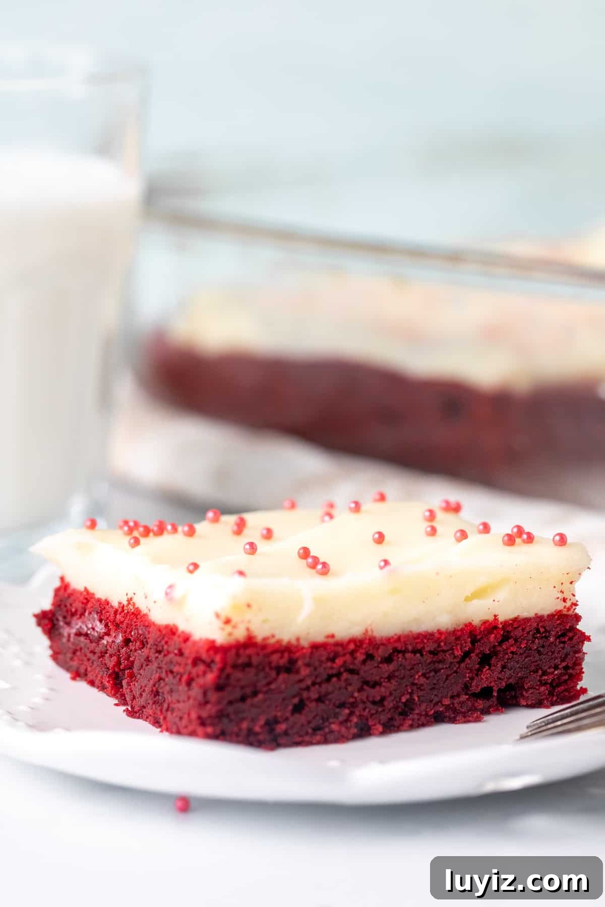Chewy Red Velvet Cookie Bars Recipe for Parties and Gifts 3 Red velvet cookie bar on a plate, topped with cream cheese frosting and sprinkles