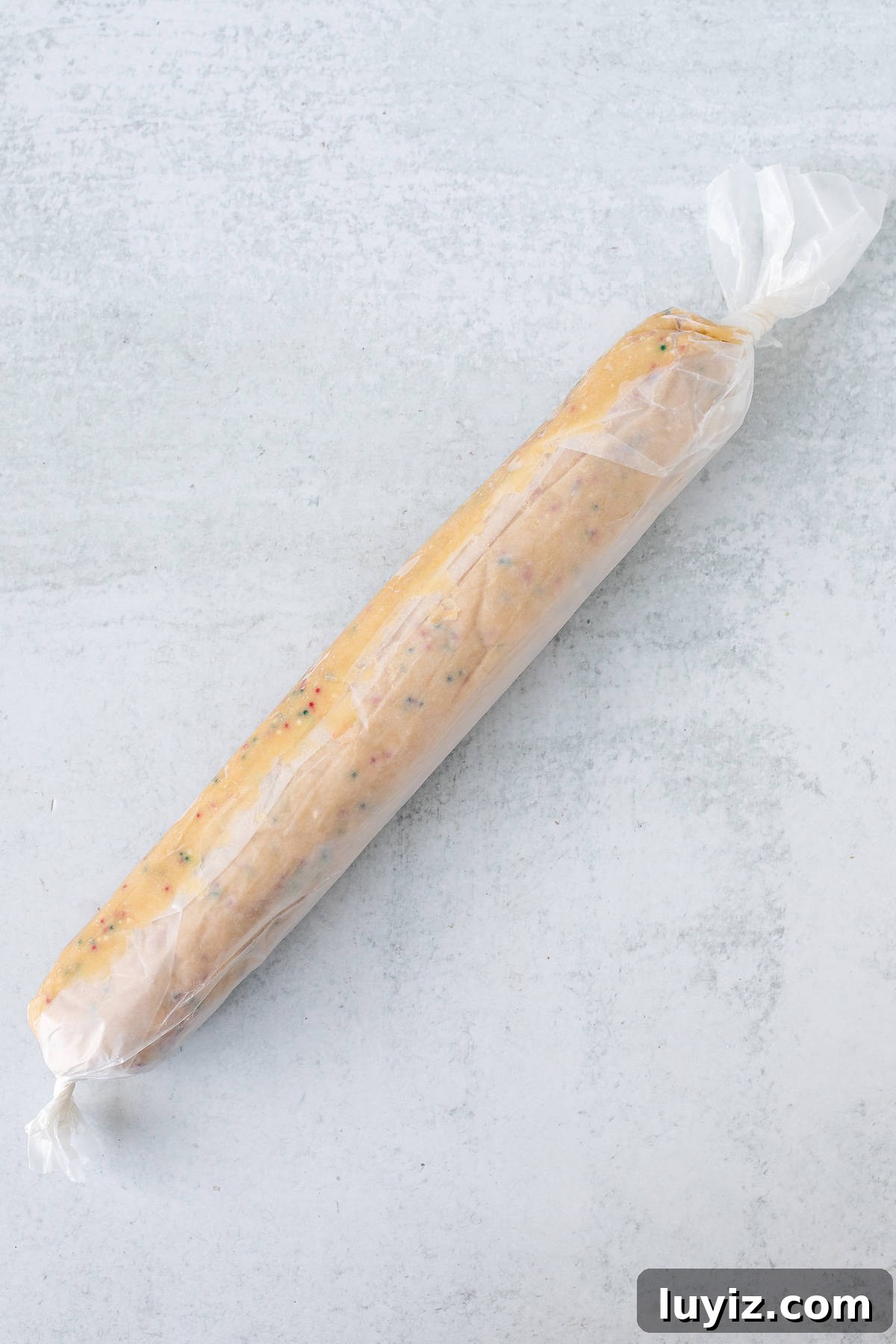 Christmas Sprinkle Slice-and-Bake Cookies: Festive Holiday Recipe 4 Cookie dough log wrapped in wax paper with the ends twisted