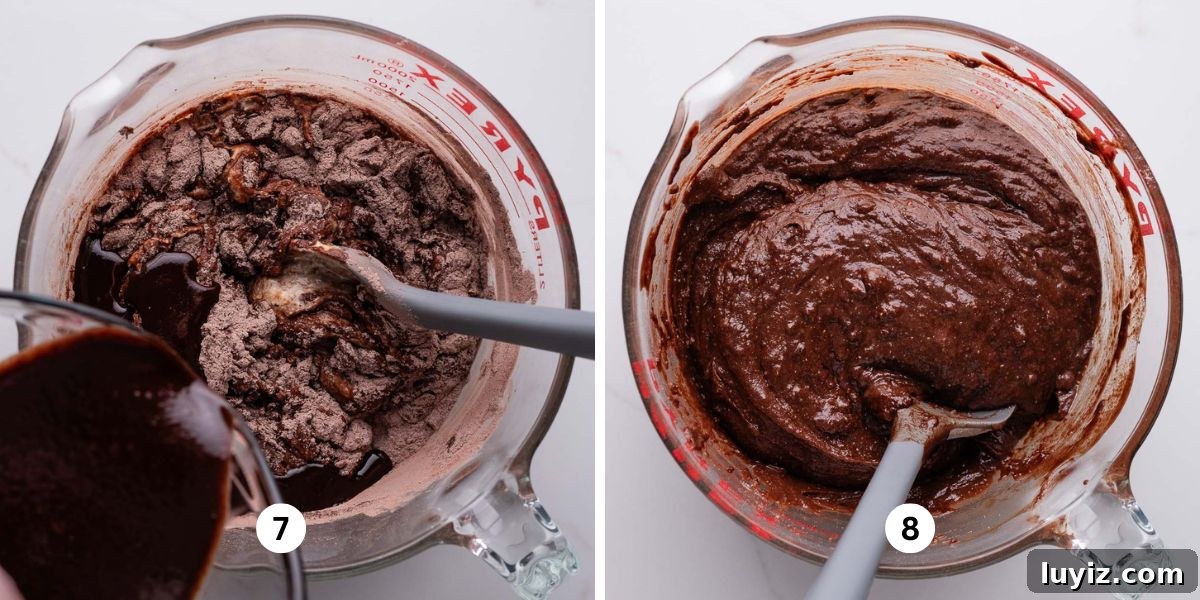 Decadent Chocolate Ricotta Cake Recipe for Moist, Fluffy Results 8 Stirring dry and wet ingredients together with a grey spatula in a glass mixing bowl on a white marbled background.