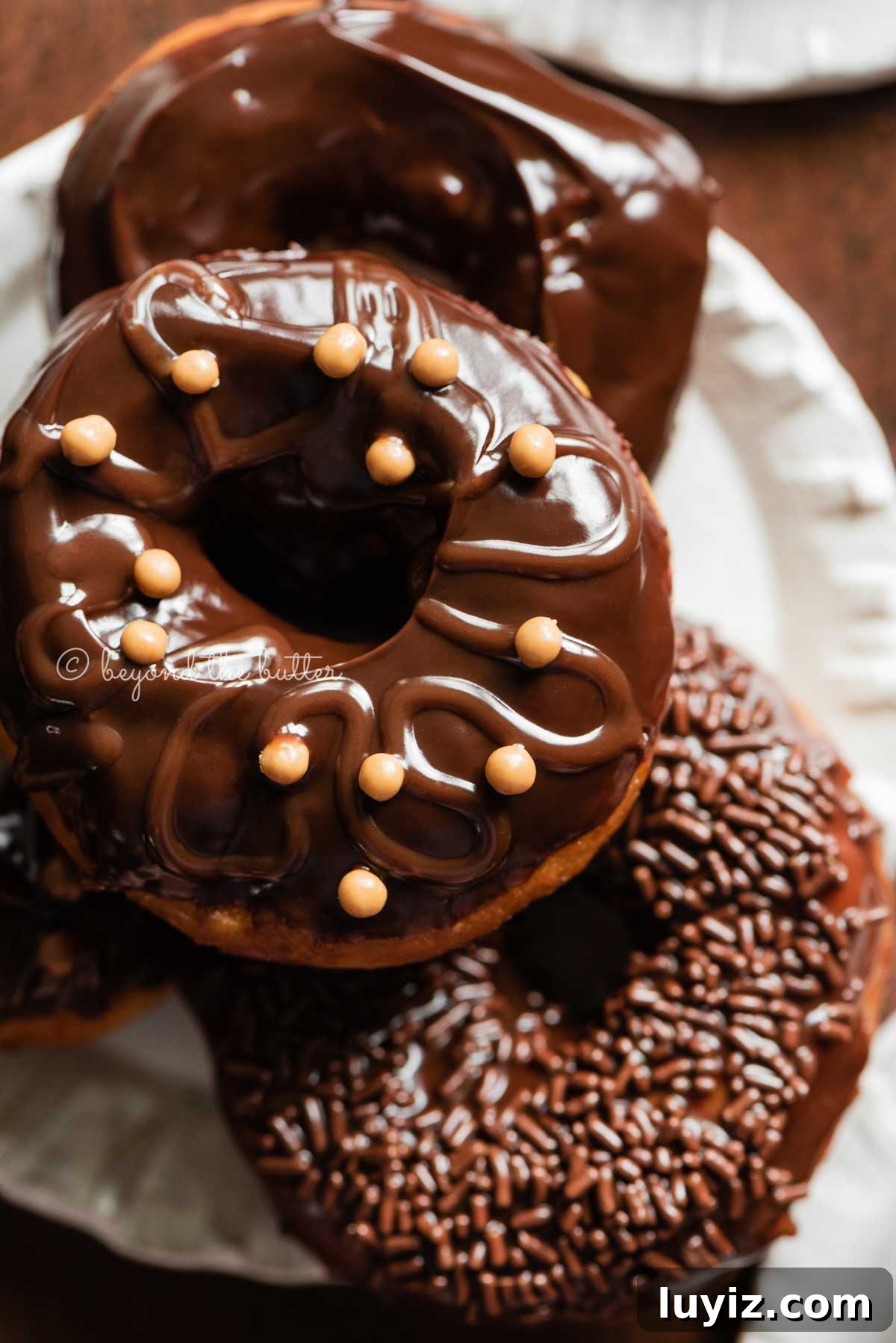 Homemade Donuts from Scratch: Classic Recipe for Soft, Fluffy Donuts 3 Easy homemade donuts fro scratch topped with chocolate glaze stacked on a dessert plate | All Images © Beyond the Butter™